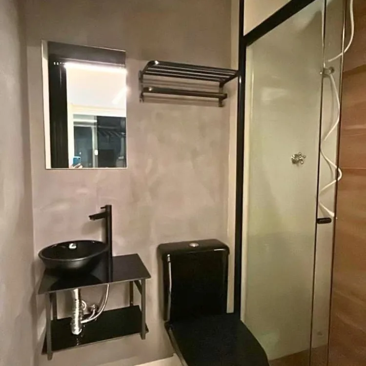 Banheiro com parede em cimento queimado cinza, acabamento decorativo da Alpha Empreiteira
